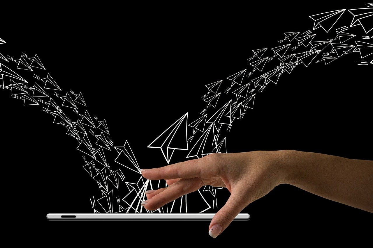 カラフルなスマートフォンと手、紙飛行機 - メールの直感的な受送信をイメージした画像